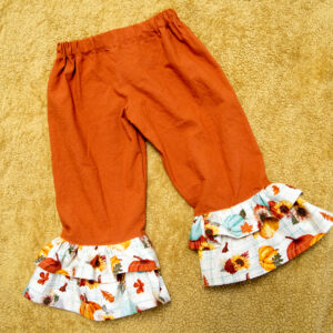 Orange pants with white Fall fabric ruffles. 2 ruffles at the bottom of the pants