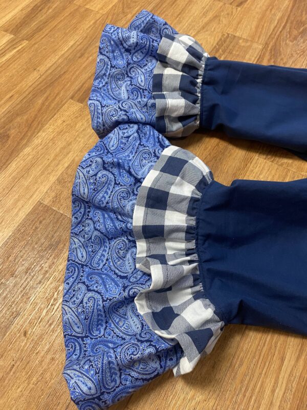 Blue paisley pattern ruffle under a blue checkered ruffle with a solid navy pants